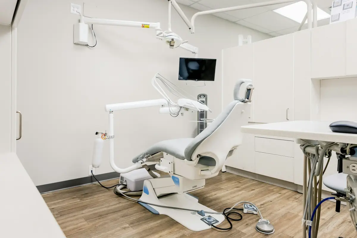 A bright, empty dental treatment room with a patient chair and light wood floor